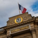 French Parliament clock at gate and national flav